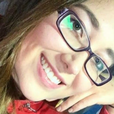 la imagen puede contener a una mujer de cabello castaño ,tiene puestos unos lentes cuadrados y sonrie.